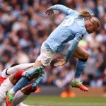 Aksi duel udara agresif antara penyerang Manchester City, Erling Haaland, dan bek Arsenal, Gabriel Magalhaes, dalam pertandingan Liga Inggris.